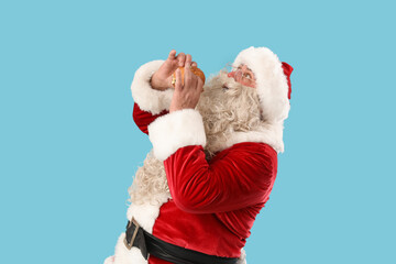 Santa Claus eating tasty burger on blue background
