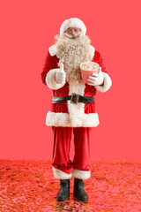 Santa Claus with tasty popcorn showing thumb-up on red background