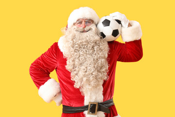 Santa Claus with soccer ball on yellow background