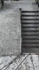 An unfinished, weathered staircase from an abandoned construction site. The rough concrete surface and worn steps evoke a sense of neglect and the passage of time.