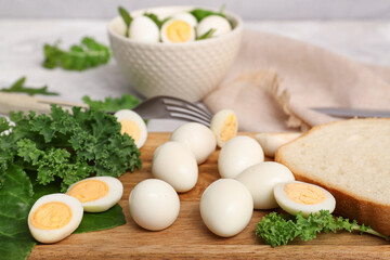 Wooden board with fresh boiled quail eggs and greens on table, closeup