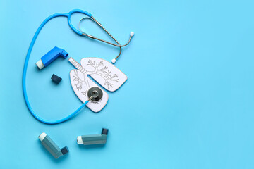 Composition with inhalers, paper lungs and stethoscope on blue background