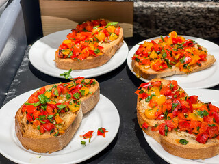 Bruschetta fresh italian Antipasti appetizers roastet bread with chopped tomatos and peppers on white plates restaurant display