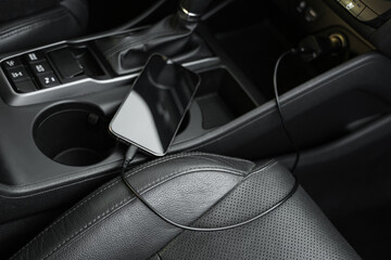 Mobile phone with charging cable in car, closeup