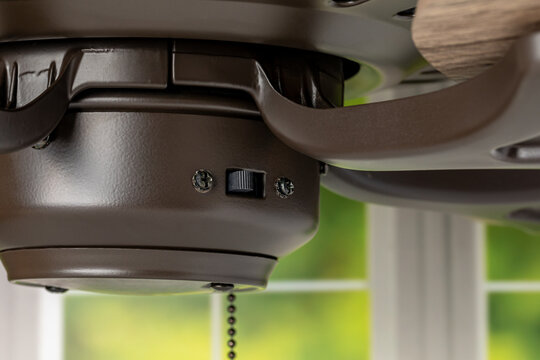 Direction switch on ceiling fan. Indoor heating and cooling savings, energy conservation, and ceiling fan blade rotation concept.