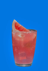 Pink colored cocktail garnished with grapefruit on a blue background.