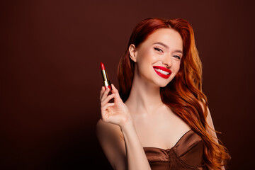 Obraz premium Photo of attractive happy lady model advertising cosmetics matte pomade isolated on brown color background