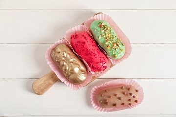 Sweet eclairs on light wooden background