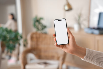Woman with blank mobile phone at home, closeup