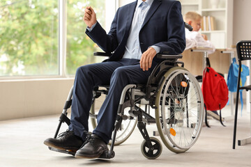 Obraz premium Male teacher in wheelchair with pointer at school