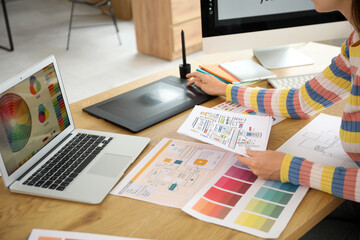 Female graphic designer with drawing working at table in office, closeup