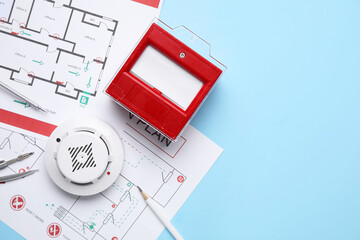 Modern smoke detector with fire call point and evacuation plans on blue background
