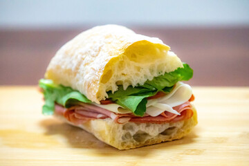 Italian mortadella bologna sandwich with arugula, tomato and cheese on ciabatta bread
