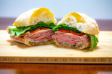 Italian mortadella bologna sandwich with arugula, tomato and cheese on ciabatta bread