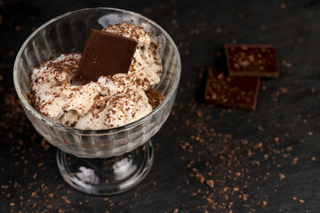 white creamy ice cream with pieces and crumbs of chocolate in a glass bowl