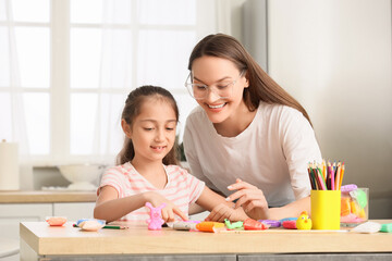 Little girl with her mother sculpting from plasticine in kitchen