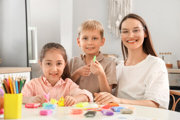 Fototapeta premium Mother with her little children sculpting from plasticine in kitchen