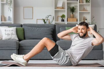 Sporty young man exercising on yoga mat at home