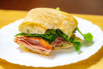 Italian mortadella bologna sandwich with arugula, tomato and cheese on ciabatta bread