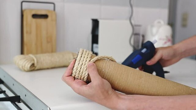 A man repairs a cat house using a hot glue gun.