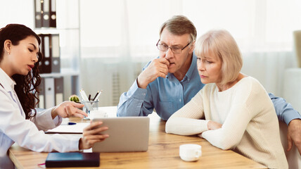 Senior Couple Discussing Medical Test Results With Doctor, Physician Showing Diagnosis On Tablet