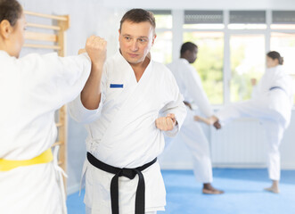 Fototapeta premium Irate middle-aged male karate practitioner fighting with his opponent in sports hall
