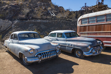 Abandoned vintage rusted vehicles in a desert junkyard
