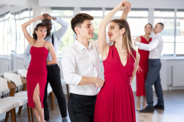 With unhurried music, guy and young woman in couple spins to rhythm of waltz during lesson for...