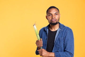 African american guy pretending to start a fight with a leek, holding produce as a bat against...