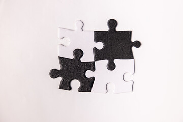 Opposite day concept using white and black puzzle pieces on a white background.