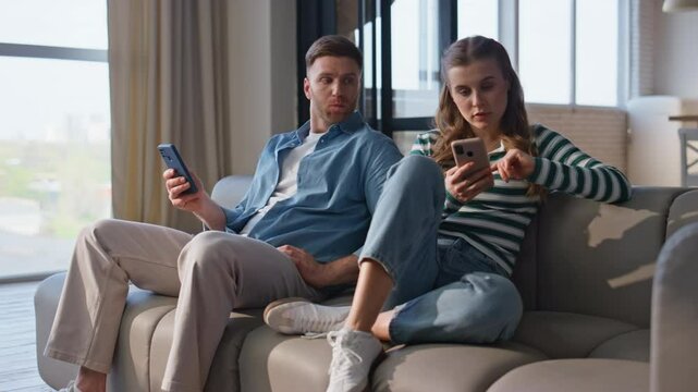 Offended couple browsing smartphones at domestic weekend. Internet addicted pair