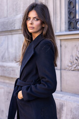 A woman showcases street fashion, posing on the street in autumn