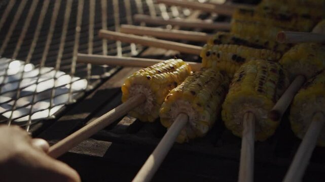 Elote siendo volteado en parrilla para un evento.