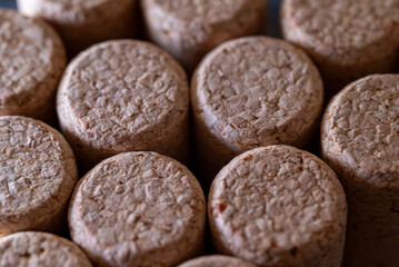 A bunch of cork stoppers are piled on top of each other. The stoppers are brown and have a rough texture. Concept of rustic charm and a connection to nature