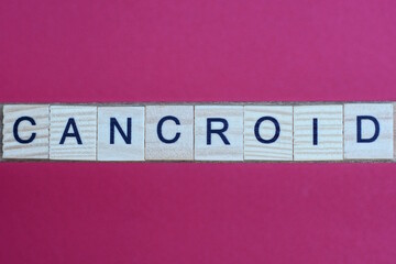 word cancroid from gray wooden small letters with black font on an red table