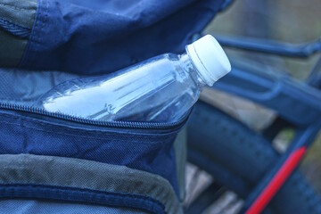 one white plastic water bottle lies in the pocket of the bag on the bicycle on the street