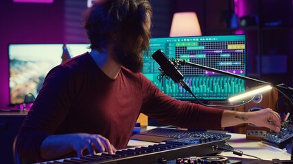 Artist singing a song at microphone and playing electronic piano to create music in home studio....