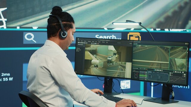 Indian call center operator giving updates about order to clients, ensuring fast delivery from observation room. Employee searching for routes without traffic on CCTV real time footage. Camera A.