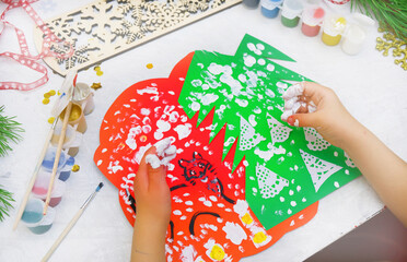 Child making a greeting card  Craft for children. Nice greeting card with a Christmas snowy forest. . Top view