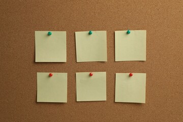 Beige paper notes pinned to cork board
