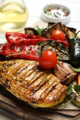 Delicious grilled vegetables and chicken breast on table, closeup