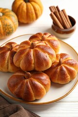 Tasty pumpkin shaped buns and ingredients on white wooden table, closeup