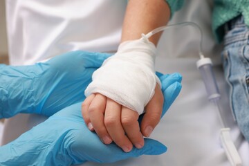 Fototapeta premium Doctor and child with IV drip in hospital, closeup