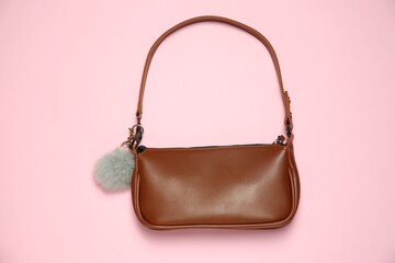 Brown bag with grey faux fur keychain on pink background, top view