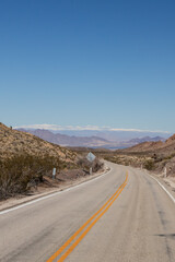 Two lane road through the desert with mountains in background