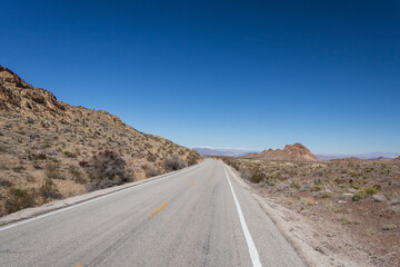 Two lane road through the desert with mountains in background