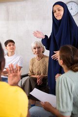 Young asian woman in burqa tells an interesting story or conducts training for adult students of...