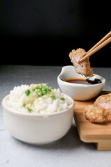 Hand use chopstick eating Japanese tonkatsu fried pork cutlet recipe with sweet sour sauce and rice on wooden broad. Asian food.