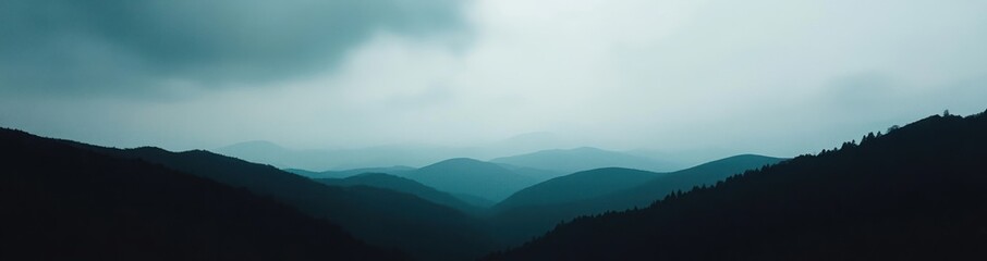 A misty mountain range with a light blue sky in the background.