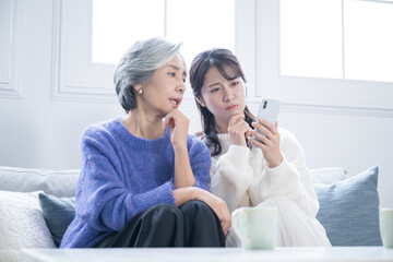 スマホの使い方がわからなくて悩む親子　困る、悩み詐欺などネガティブイメージ